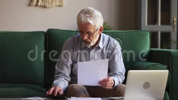 一位严肃的老人手里拿着纸在家里计算家庭账单视频的预览图