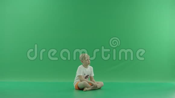 一个年轻体贴的金发男孩穿着休闲的夏装坐在地板上梦到了什么他坐在那里视频的预览图