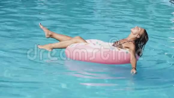 有魅力的女人正在游泳池里的充气橡胶圈上游泳视频的预览图