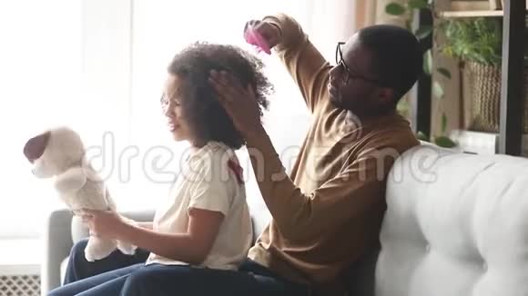 可爱的黑人父亲正在给小女儿梳头视频的预览图
