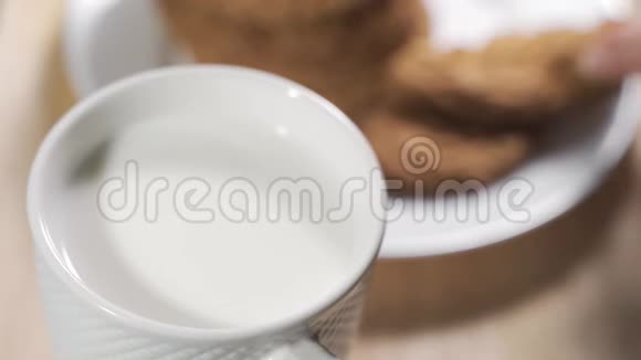 在一个温暖的早晨一个女人用手在牛奶杯里灌了一块饼干视频的预览图