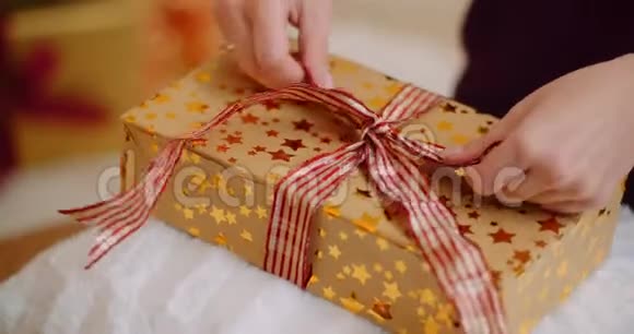 妇女在圣诞礼物上绑丝带的剪裁视频的预览图
