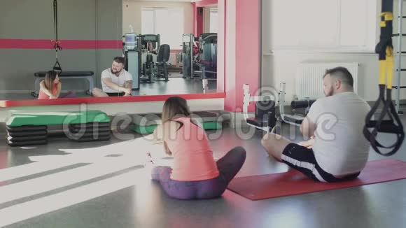 人和私人教练在健身中心训练后休息厚肥胖的家伙私人苗条的教练做体育视频的预览图
