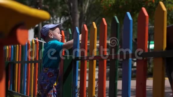小男孩正慢悠悠地呆在彩色彩虹围栏附近视频的预览图