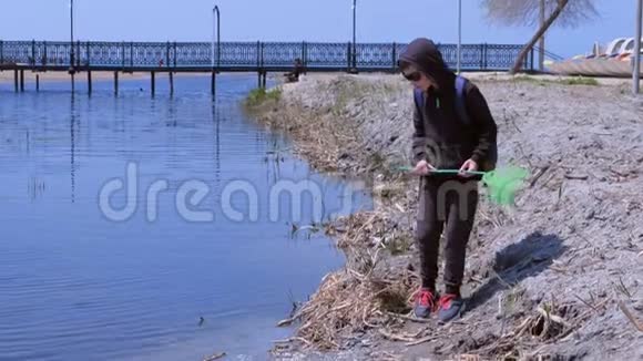 男孩正在用蝴蝶网在河上放青蛙但它跳了出来视频的预览图