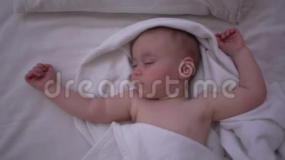 一个蹒跚学步的孩子睡在大床上双手抬起动作缓慢视频的预览图