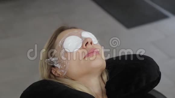 美丽的女人躺在美容院的一个程序上眼睛上有棉花垫视频的预览图