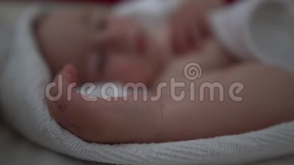 一个模糊可爱的孩子慢悠悠地睡在白色毯子下面视频的预览图