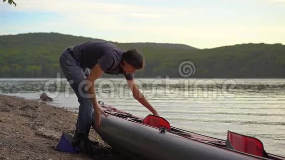 年轻人把皮艇充气准备在湖或海中划水慢镜头视频的预览图