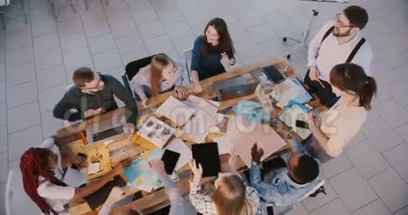俯视快乐的多民族商业团队一起在餐桌上工作与男性和女性老板一起欢笑视频的预览图