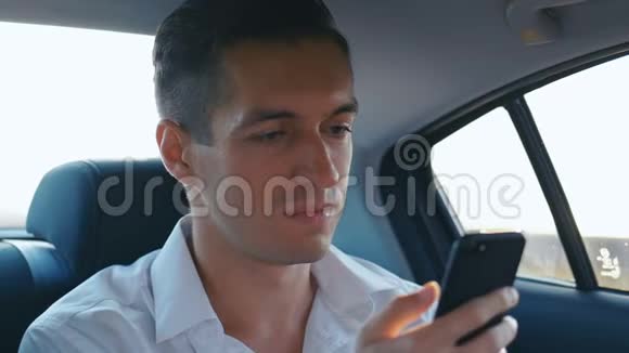 年轻的商人在开车时使用他的智能手机男人正在检查指甲帽子或新衣服视频的预览图