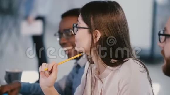 快乐年轻漂亮的商务女性戴着眼镜倾听并在多民族公司员工会议上提供想法视频的预览图