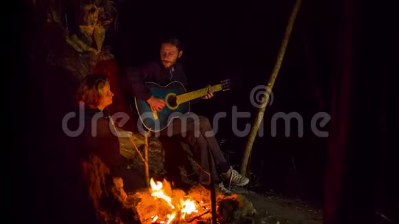 年轻人在篝火晚会上演奏吉他和唱歌视频的预览图