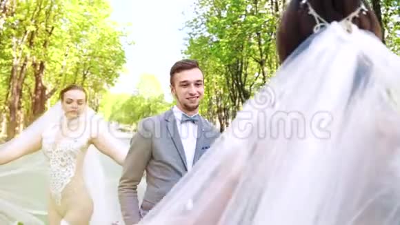 年轻时尚的新郎高兴地看到三位性感的新娘在他身边走来走去视频的预览图