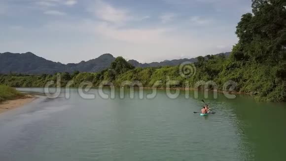 上靠背的一对夫妇乘独木舟驶向森林河岸视频的预览图