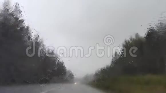 行驶在暴雨风暴中戏剧性的北斯堪的纳维亚路线雨水滴在汽车挡风玻璃上视频的预览图