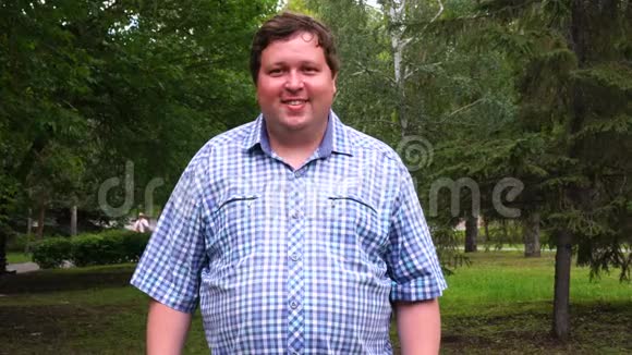 公园里一个穿格子衬衫的快乐胖子的画像视频的预览图