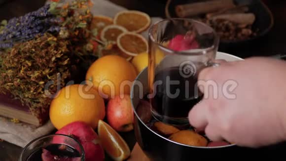 男人的手把覆盖的葡萄酒倒入透明的杯子里新鲜柠檬橙子石榴和干草本植物视频的预览图