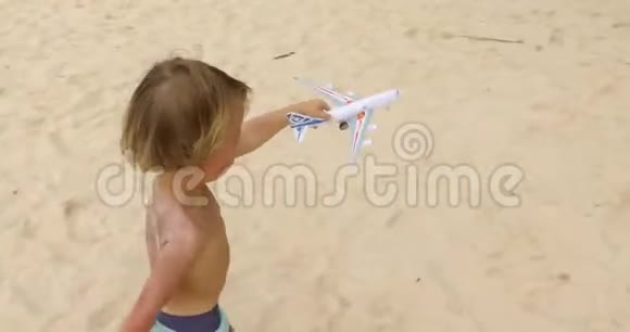 男孩在沙滩上玩玩具飞机视频的预览图