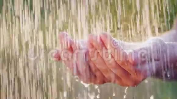 一个人握着他的手在倾盆大雨中水滴分开清凉和清洁水的概念视频的预览图