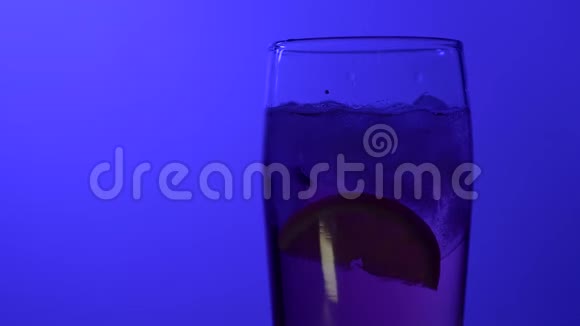 在彩色蓝色背景特写镜头上装有饮料的玻璃杯反光灯柠檬冰视频的预览图