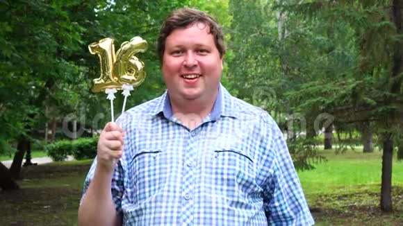 大个子拿着金色气球把16号放在户外16周年庆祝晚会视频的预览图