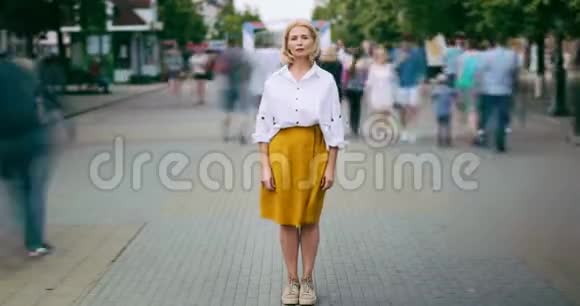 成熟的女人站在城市繁华的街道上看镜头视频的预览图