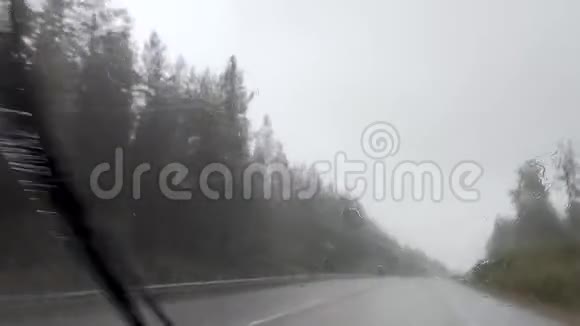 行驶在暴雨风暴中戏剧性的北斯堪的纳维亚路线雨水滴在汽车挡风玻璃上视频的预览图