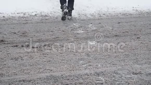 行人的双腿在冬季降雪时在白天缓慢地穿过一条雪道交通恶劣的天气条件视频的预览图