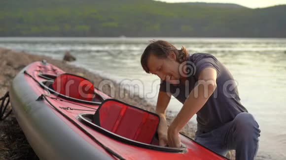 年轻人把皮艇充气准备在湖或海中划水慢镜头视频的预览图
