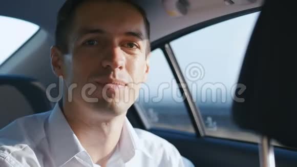 商人和司机在车里旅行的肖像穿白衬衫的年轻人坐出租车视频的预览图
