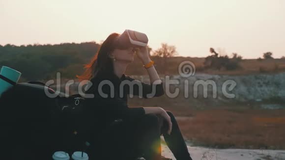 在日落时分戴着背包的年轻少女使用虚拟现实眼镜现代视频的预览图