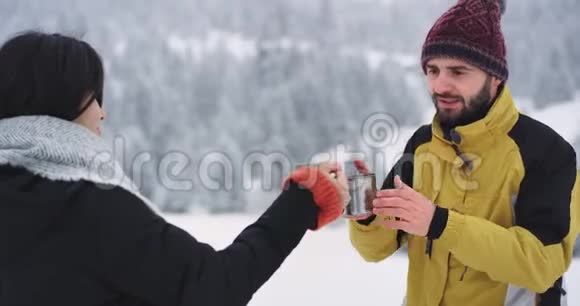 两个好朋友男女在雪林中喝热茶取暖他们开心地喝视频的预览图