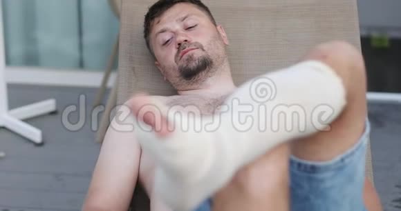 一个蓄着胡须的沮丧的人躺着一条带绷带的腿视频的预览图
