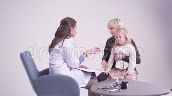 妈妈和5岁的女儿在医生办公室儿科医生做笔记视频的预览图