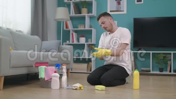 3疲倦的人打扫完地板后脱下手套视频的预览图