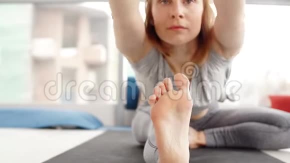 接近年轻女子练习瑜伽坐在头部到膝前弯曲锻炼视频的预览图