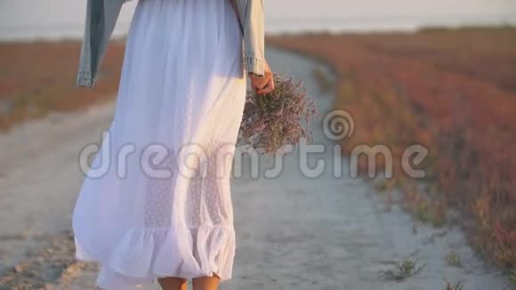 手里拿着花的女孩走在沙滩上视频的预览图