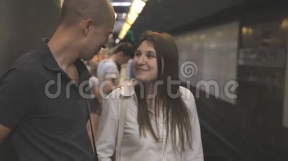 朋友男人和女人夫妇在地铁里等着火车在交谈朝方向看视频的预览图