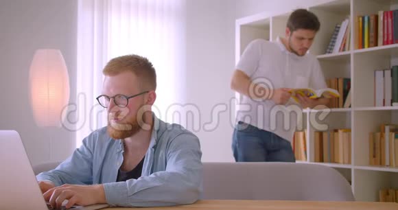 两位白种人成年商人在图书馆合作的特写照片其中一个是在笔记本电脑上打字视频的预览图