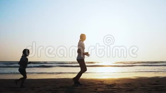 妈妈和女儿正在日落时在沙滩上慢跑视频的预览图