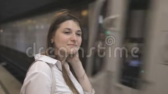一个穿着白色衬衫的女孩在地铁里等火车的到来火车到了女人把门推开视频的预览图