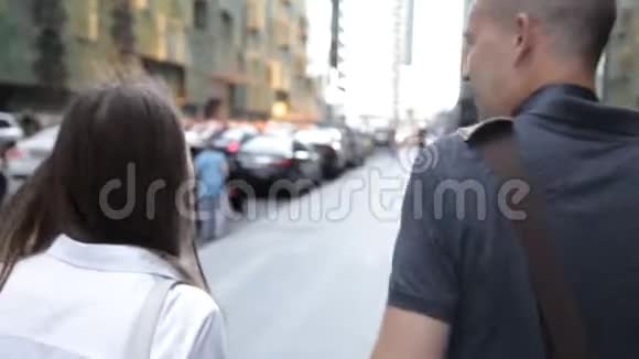 朋友一男一女走在市中心一条繁忙的街道上说话微笑着后面的景色视频的预览图