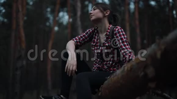 疲惫而快乐的女人坐在森林的树干上放松视频的预览图