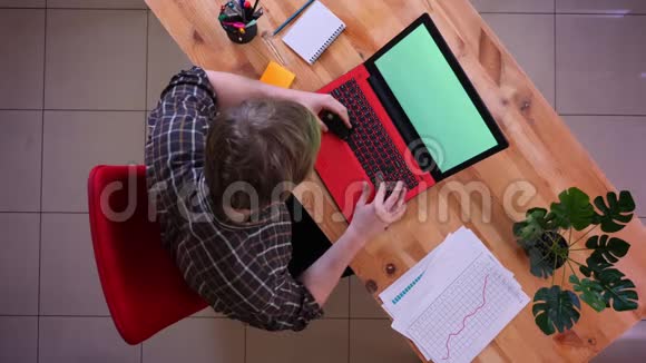 年轻的高加索商人在笔记本电脑上网上购物的特写镜头桌子上放着绿色的屏幕视频的预览图