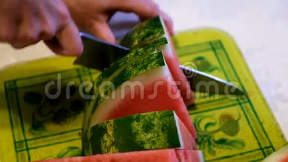 一个女人的手用刀在厨房的砧板上切西瓜视频的预览图