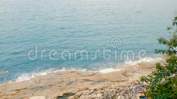 海浪拍打在岩石上泡沫般的海浪来到海岸蓝色的海水和山丘在白天视频的预览图