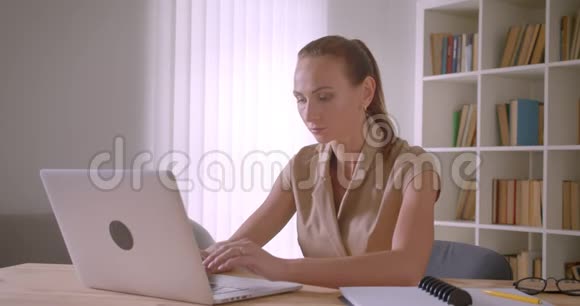 优雅的白种人女商人分析笔记本电脑上的数据在办公室里忙着写笔记本视频的预览图