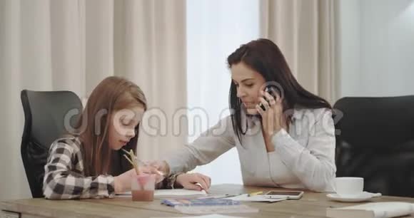 忙碌的成熟母亲早上在家工作喝咖啡和她的三个孩子在一起视频的预览图