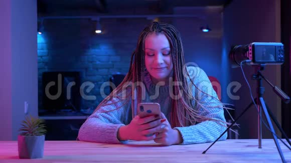 一位年轻有魅力的女性博客写手在手机上发短信微笑着快乐地现场直播视频的预览图